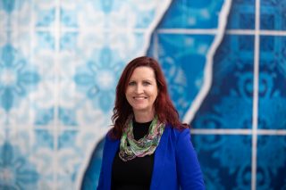 Head and shoulders picture of Katie Ellis standing infront of a blue background