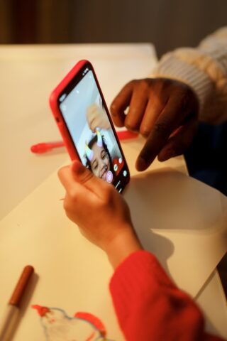 Hands from two different children holding a smart phone