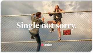 a young man and women climbing a wire fences with the words 'Single Not Sorry' written across the image as a Tinder advertisement