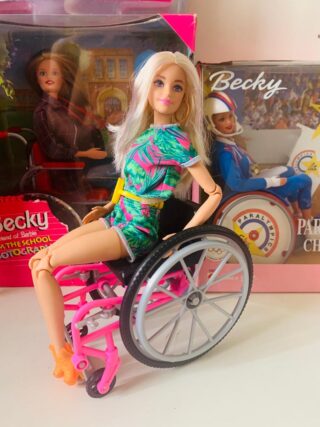 Barbie doll in a blue dress sitting in a wheelchair