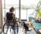 Woman in a wheelchair at home feeding her dog