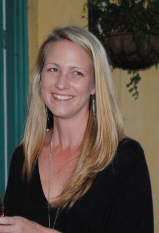 head and shoulders image of Catie Gressier smiling, wearing v neck jumper and long blonde hair
