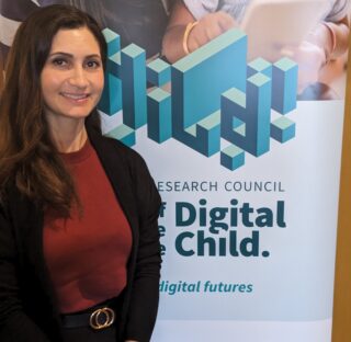 Head and upper body photo of Amanda smiling, in front of a Digital Child poster