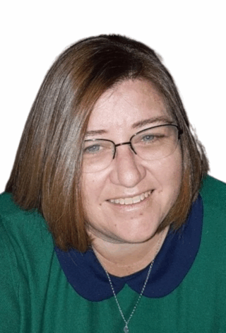 Head photograph of Kelly smiling, wearing a green and blue jumper and her glasses